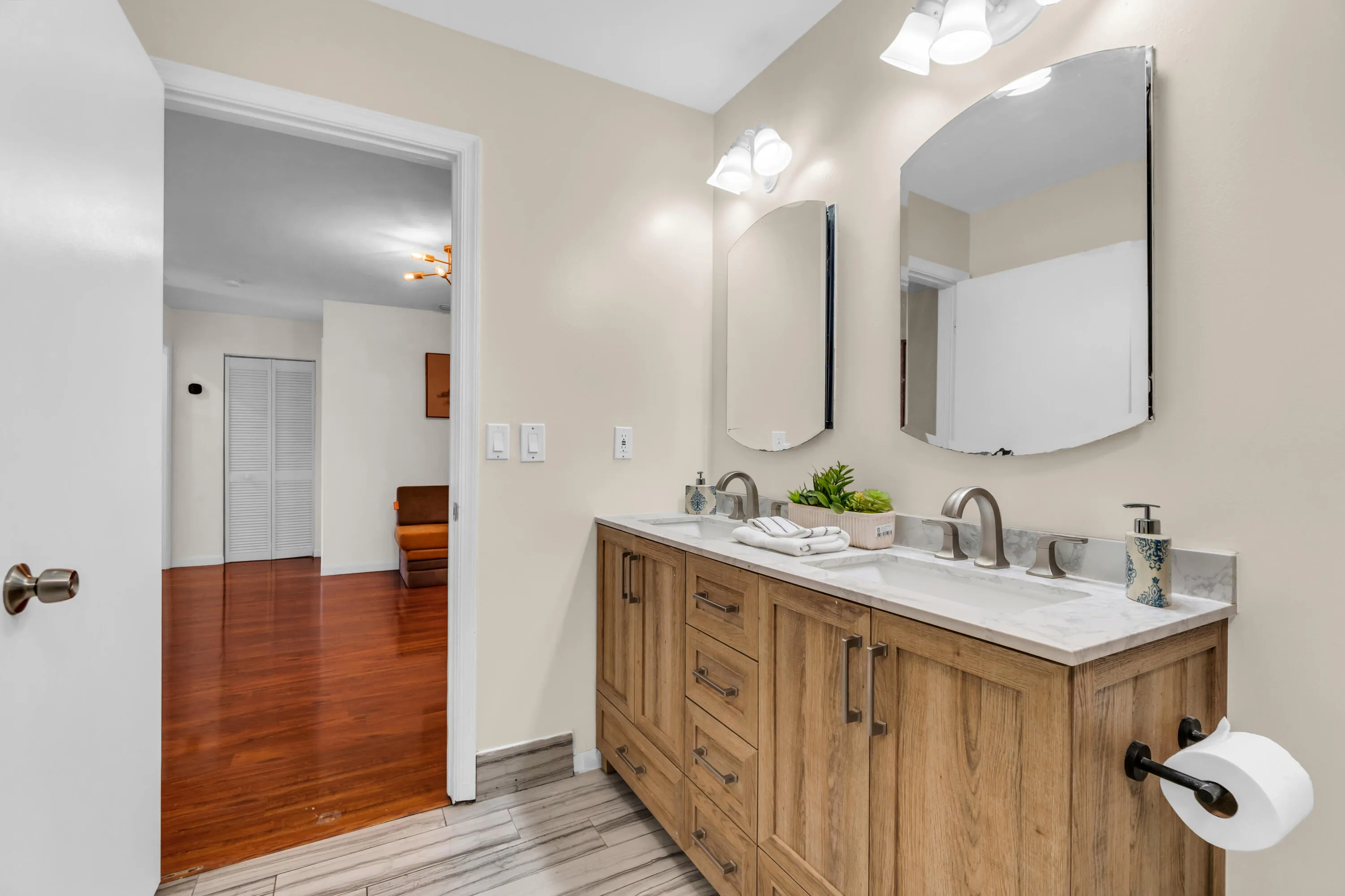 Double vanity with wood-finish cabinetry, dual undermount sinks, and a light-toned countertop