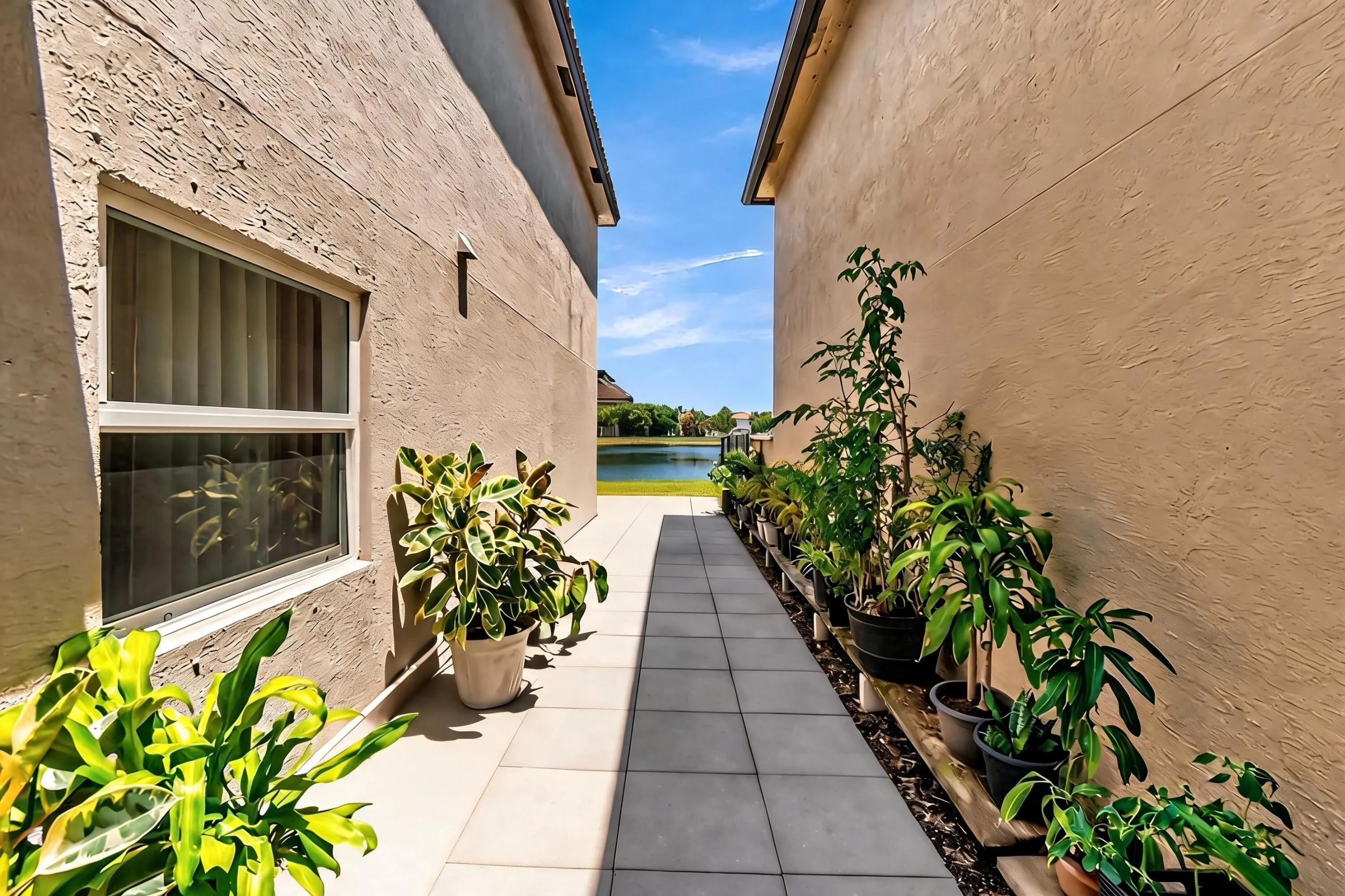 Paved walkway between stucco exteriors with a water backdrop