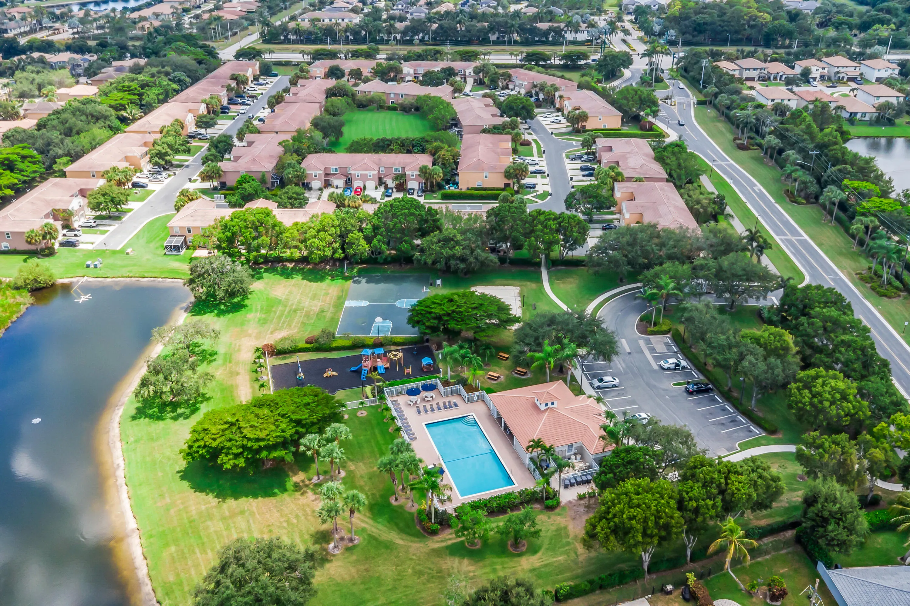 Community with a central lake, recreational pool, playground, and sports court