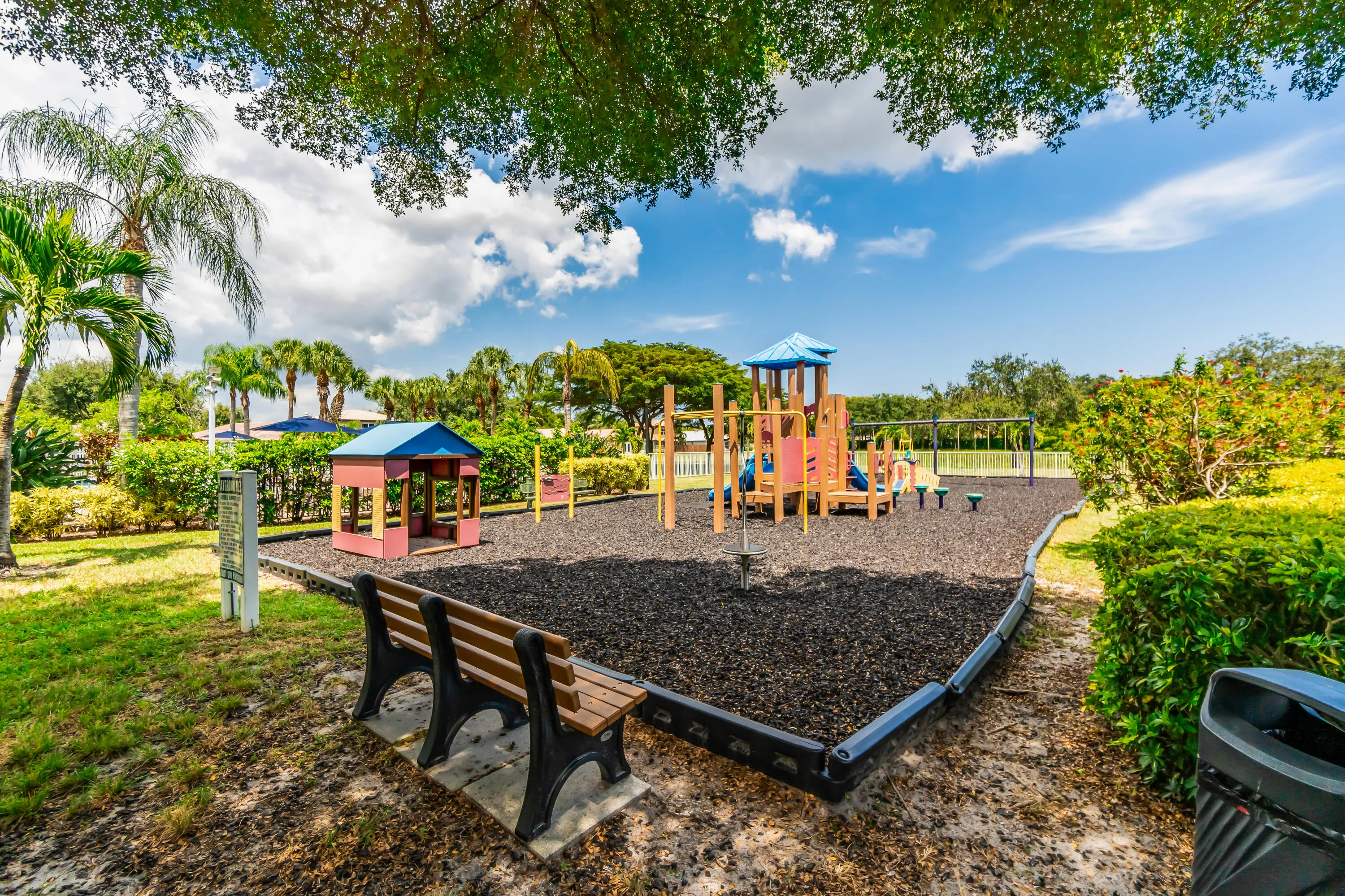 Community playground featuring a wood-and-plastic play structure, swings, and a playhouse