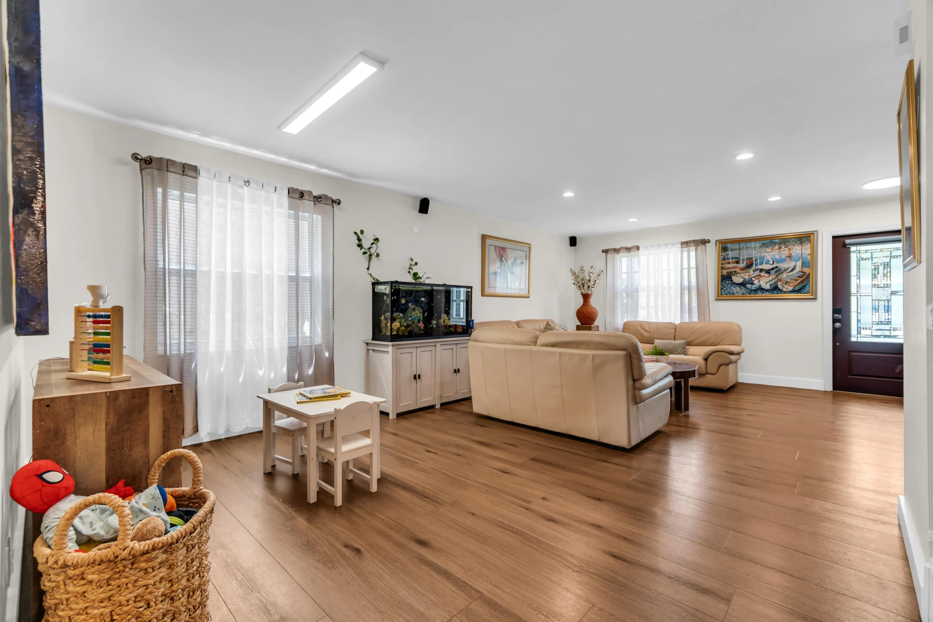 Spacious living area featuring wood-finish flooring, recessed lighting, and a transom window on the entry door