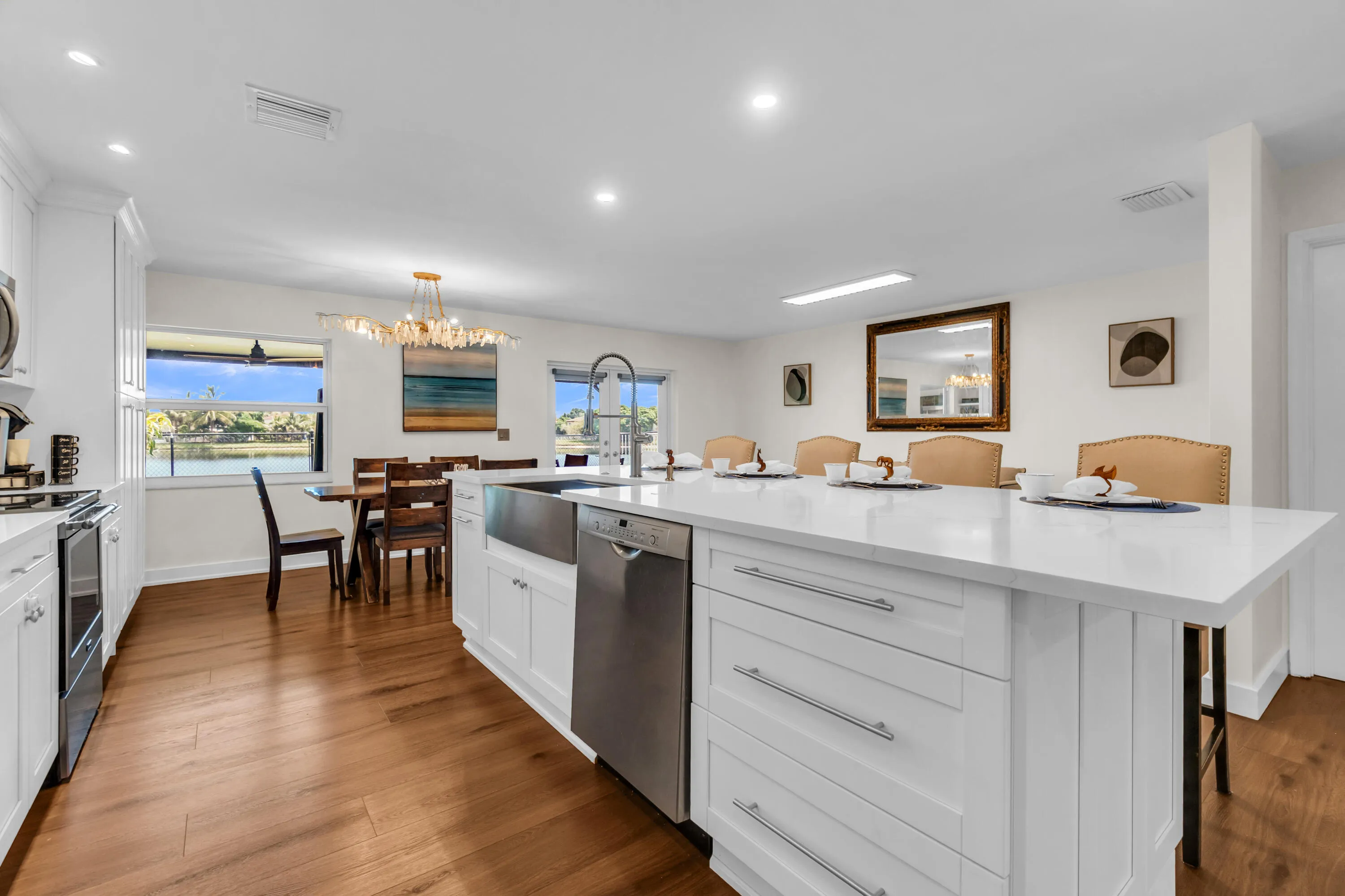 White shaker cabinetry, stainless steel appliances, wood-finish flooring, white countertop island, and an apron front sink