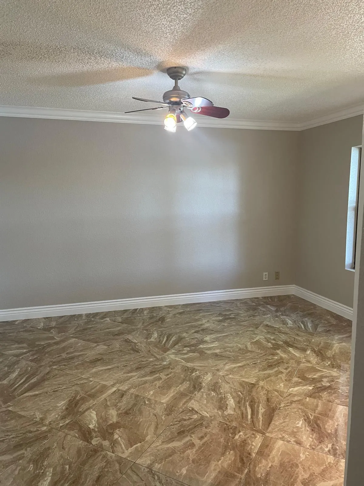 Textured ceiling with a ceiling fan light fixture, crown molding, neutral wall color, and tile flooring
