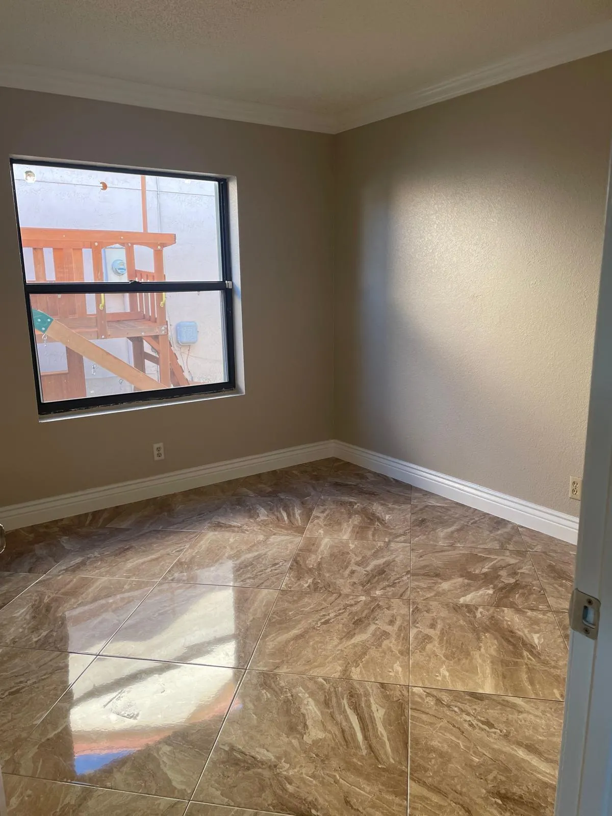 Polished tile flooring, neutral wall tones, white crown molding, and a double-hung window
