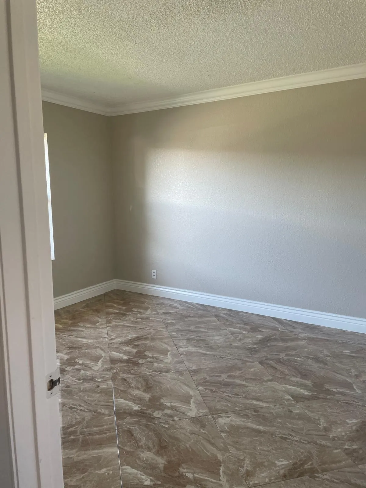 Neutral wall color, crown molding, wide baseboards, and patterned tile flooring