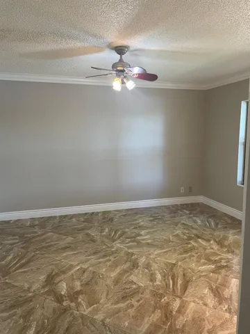 Textured ceiling with a ceiling fan light fixture, crown molding, neutral wall color, and tile flooring