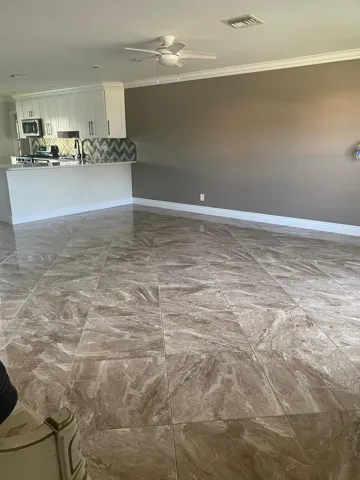 Contemporary kitchen featuring white cabinetry, stainless steel appliances, a chevron pattern backsplash, and a breakfast bar