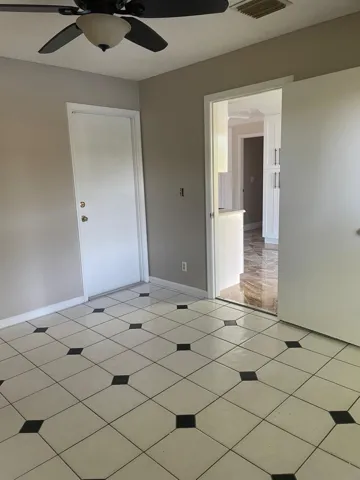 Ceiling fan with integrated lighting, tile flooring with decorative black accents, interior door, and open doorway