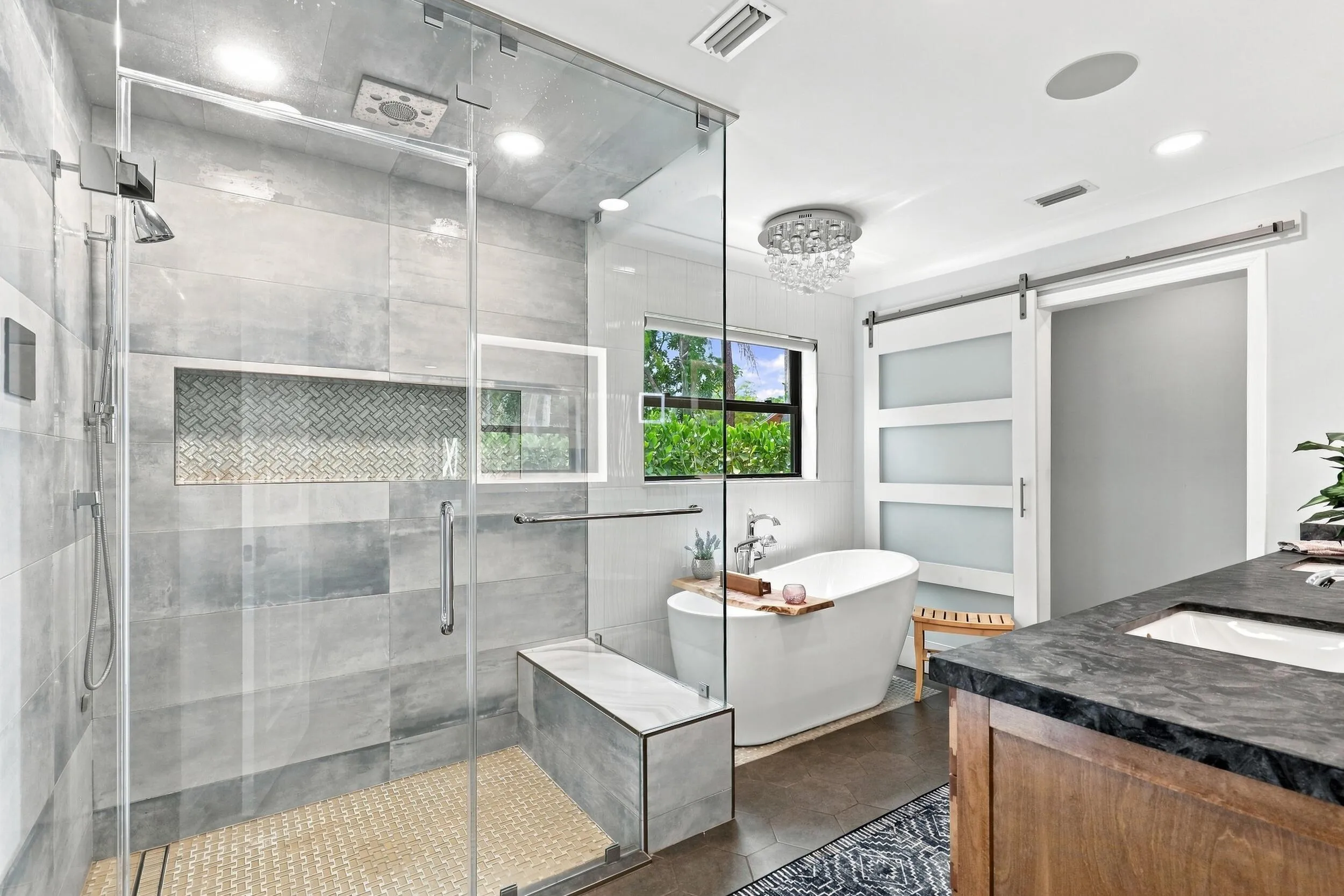 Spacious primary bath featuring a glass-enclosed shower, freestanding soaking tub, dual vanity, and modern finishes.