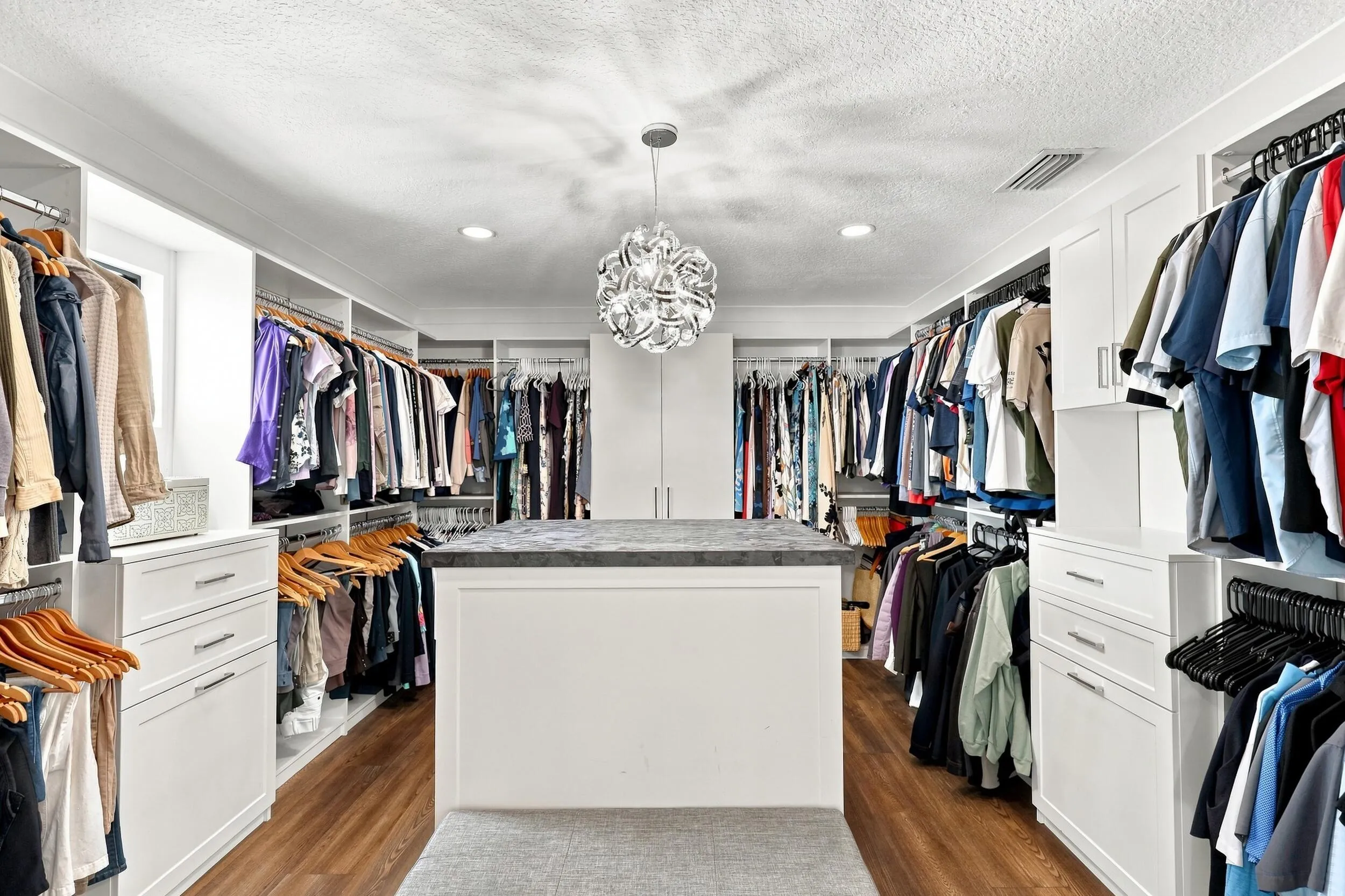 Impressive walk-in closet featuring custom built-in storage, extensive hanging space, and a center island.