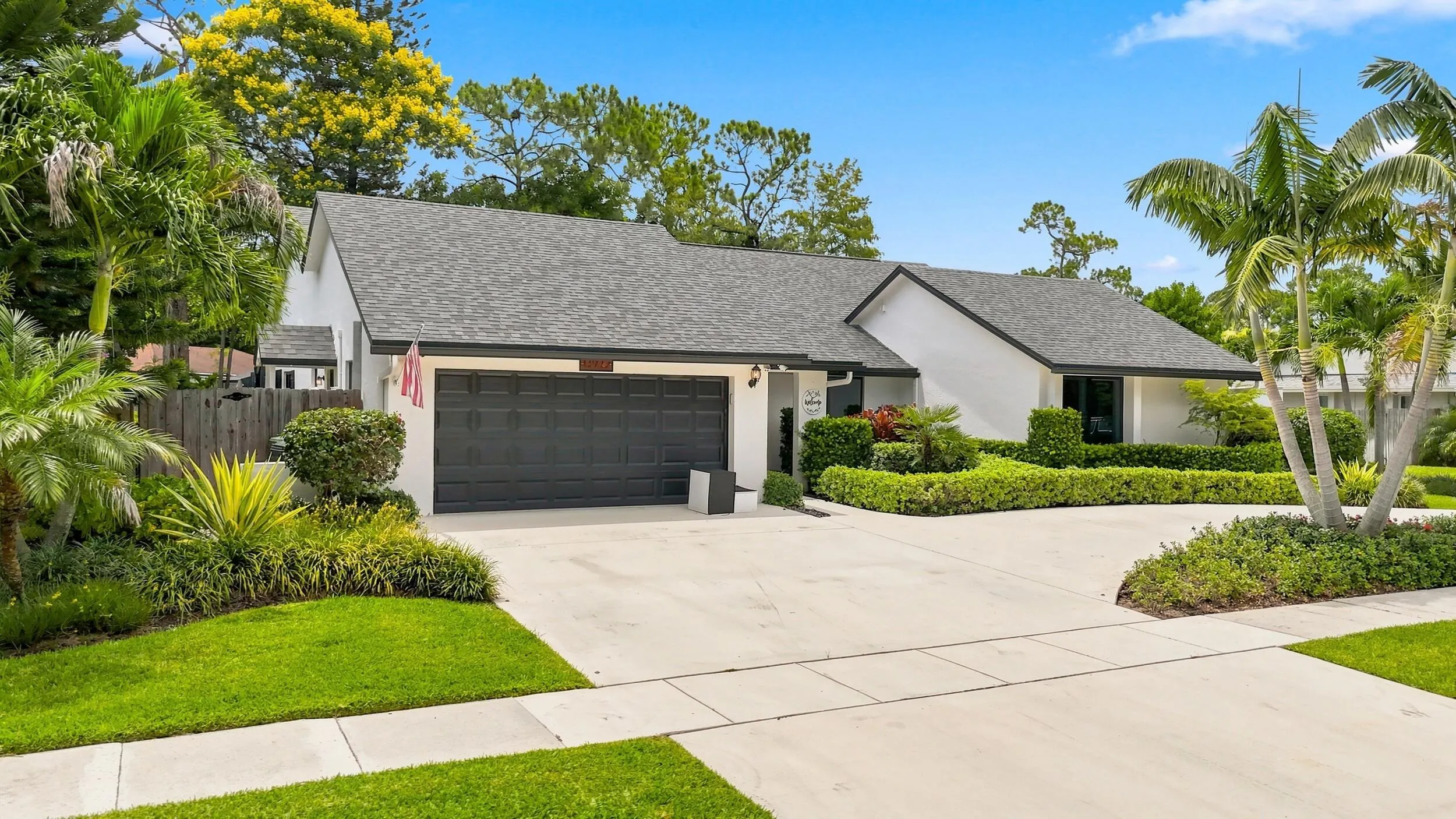 Welcoming exterior view showcasing the driveway, lush landscaping, and attractive single-story design.