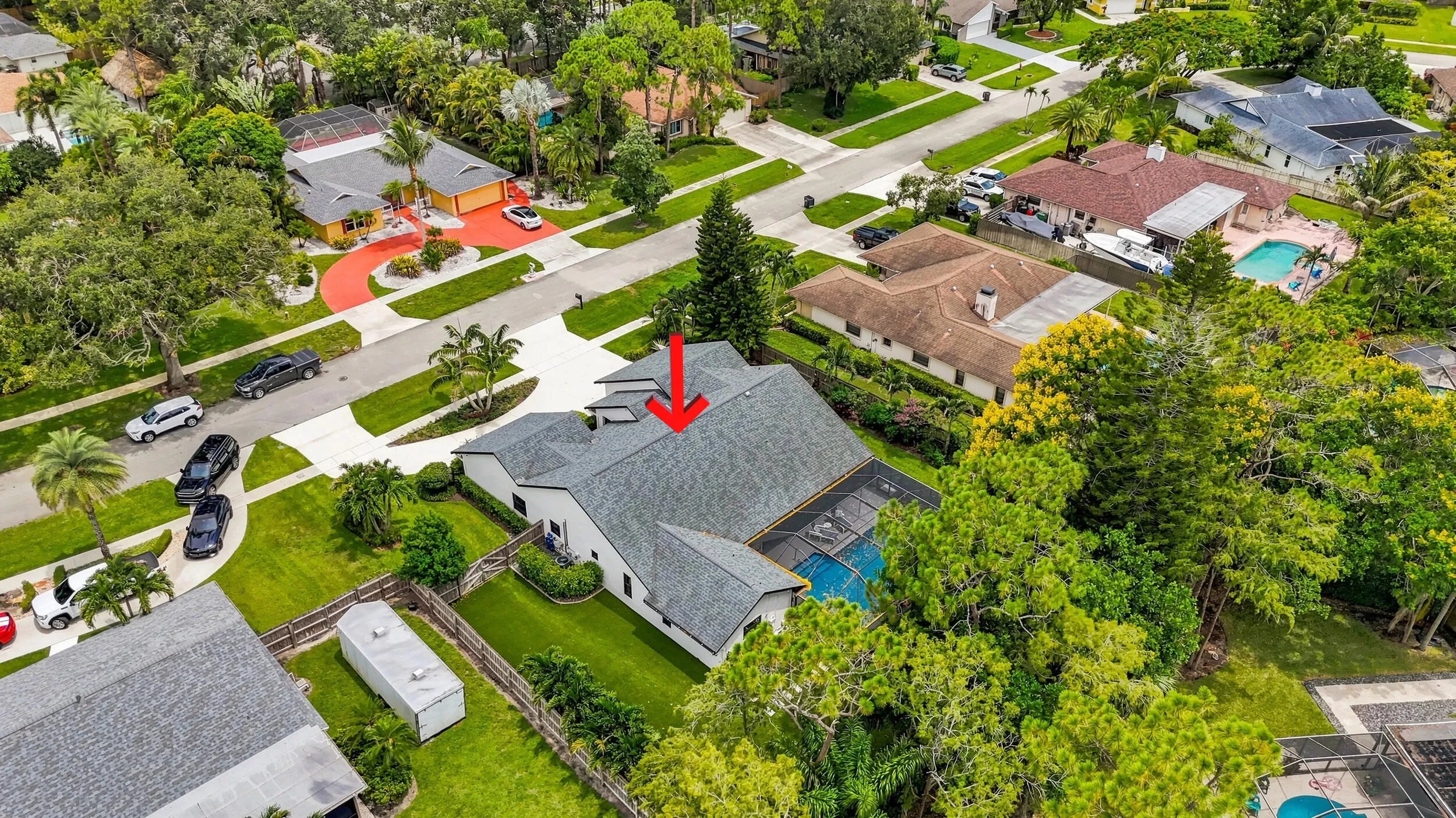 Elevated aerial view highlighting the home, lot, pool enclosure, and surrounding neighborhood.