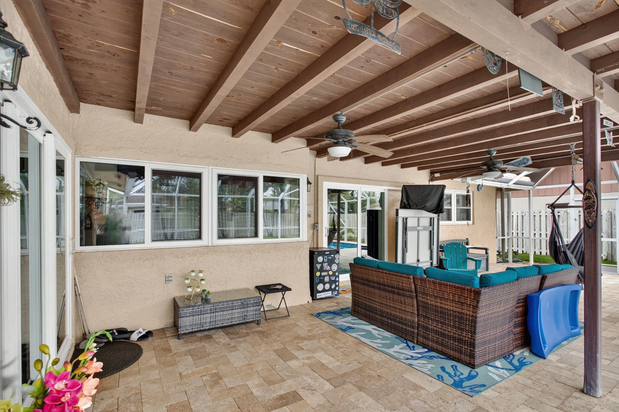 Covered patio with exposed wood beam ceiling, ceiling fans, and tiled flooring