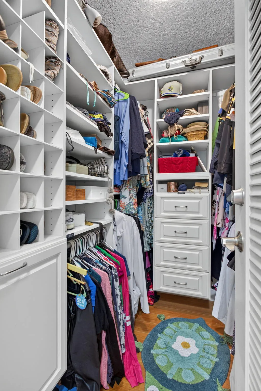 Custom closet system featuring white built-in shelving, multiple hanging rods, and integrated drawer storage