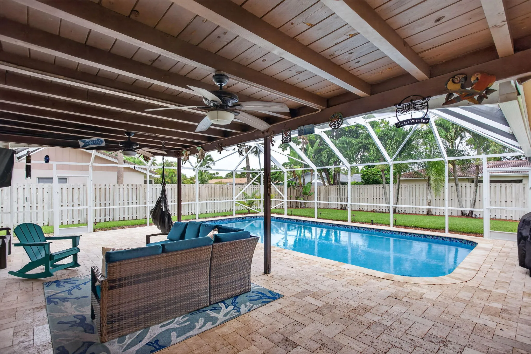Expansive covered patio with exposed wood beam ceiling, multiple ceiling fans, and paver flooring