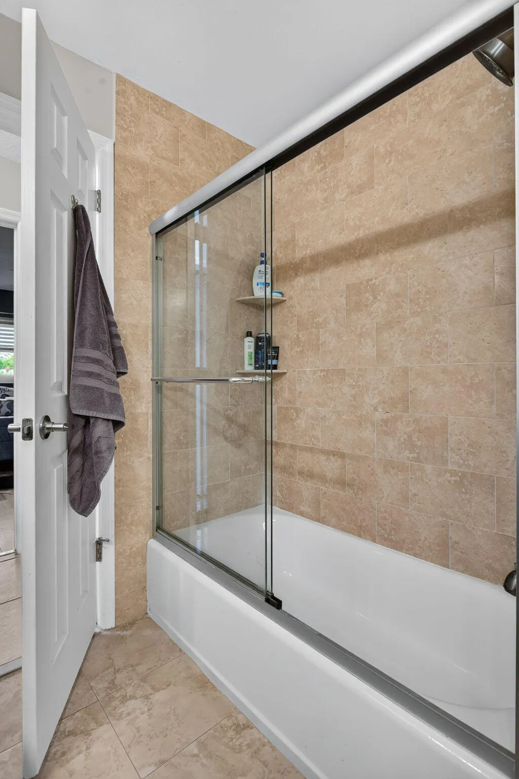 Full bathroom featuring a shower-tub combination with sliding glass doors, tiled walls, and a built-in shower shelf