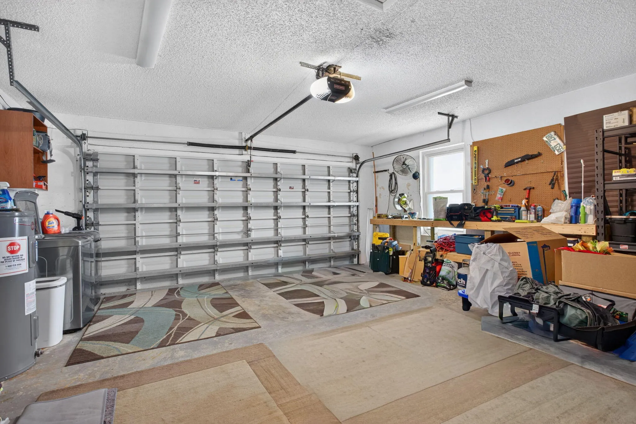 Garage space with a single overhead door, built-in workbench, and overhead lighting