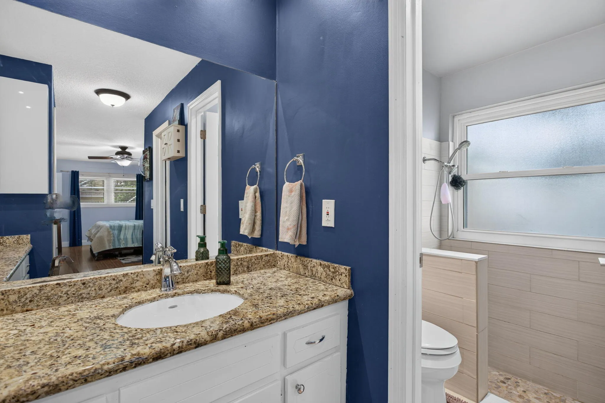 Bathroom featuring a single vanity with stone countertop, undermount sink, and chrome faucet