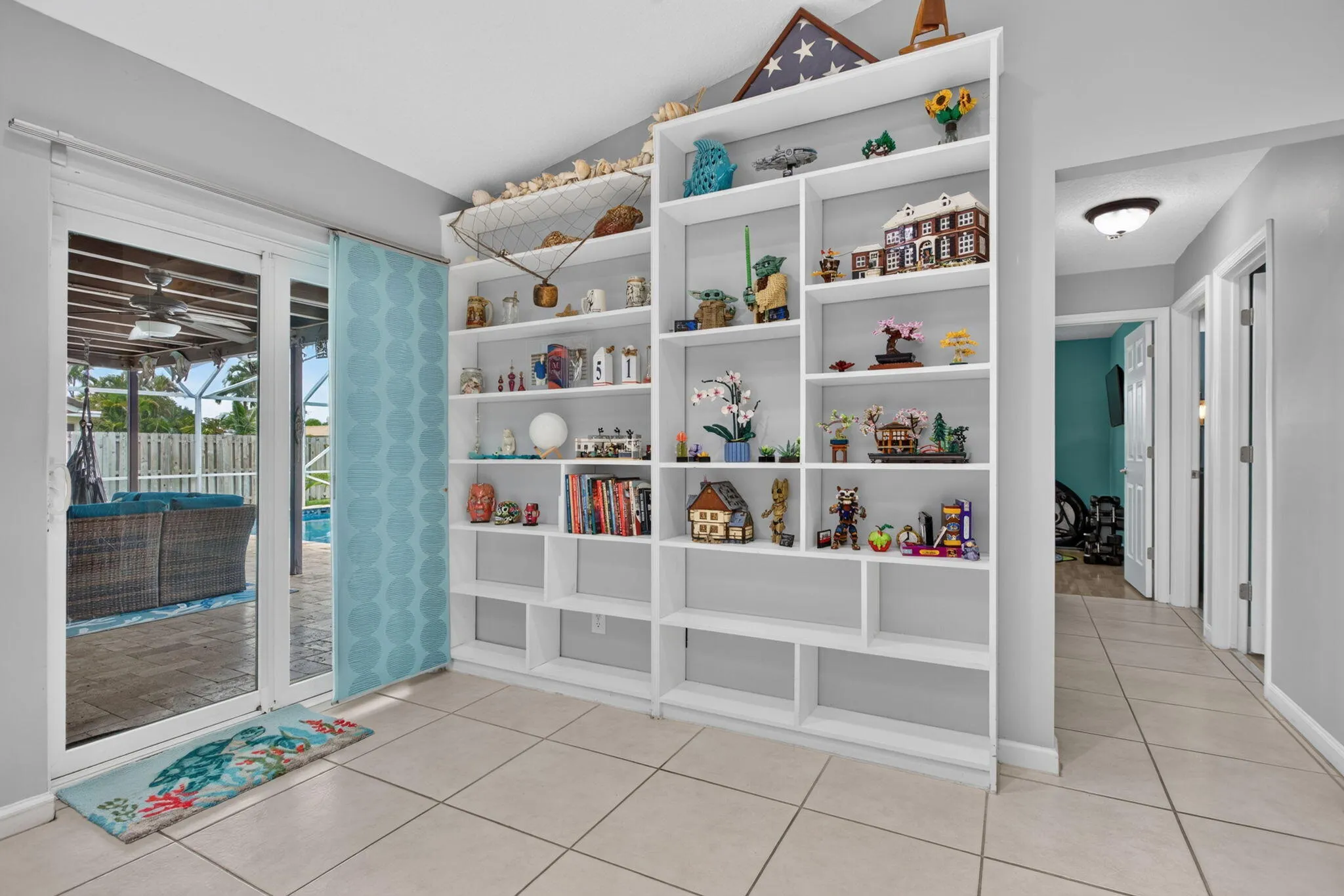 Built-in shelving with varied display configurations, tile flooring, and sliding glass doors leading to a screened patio