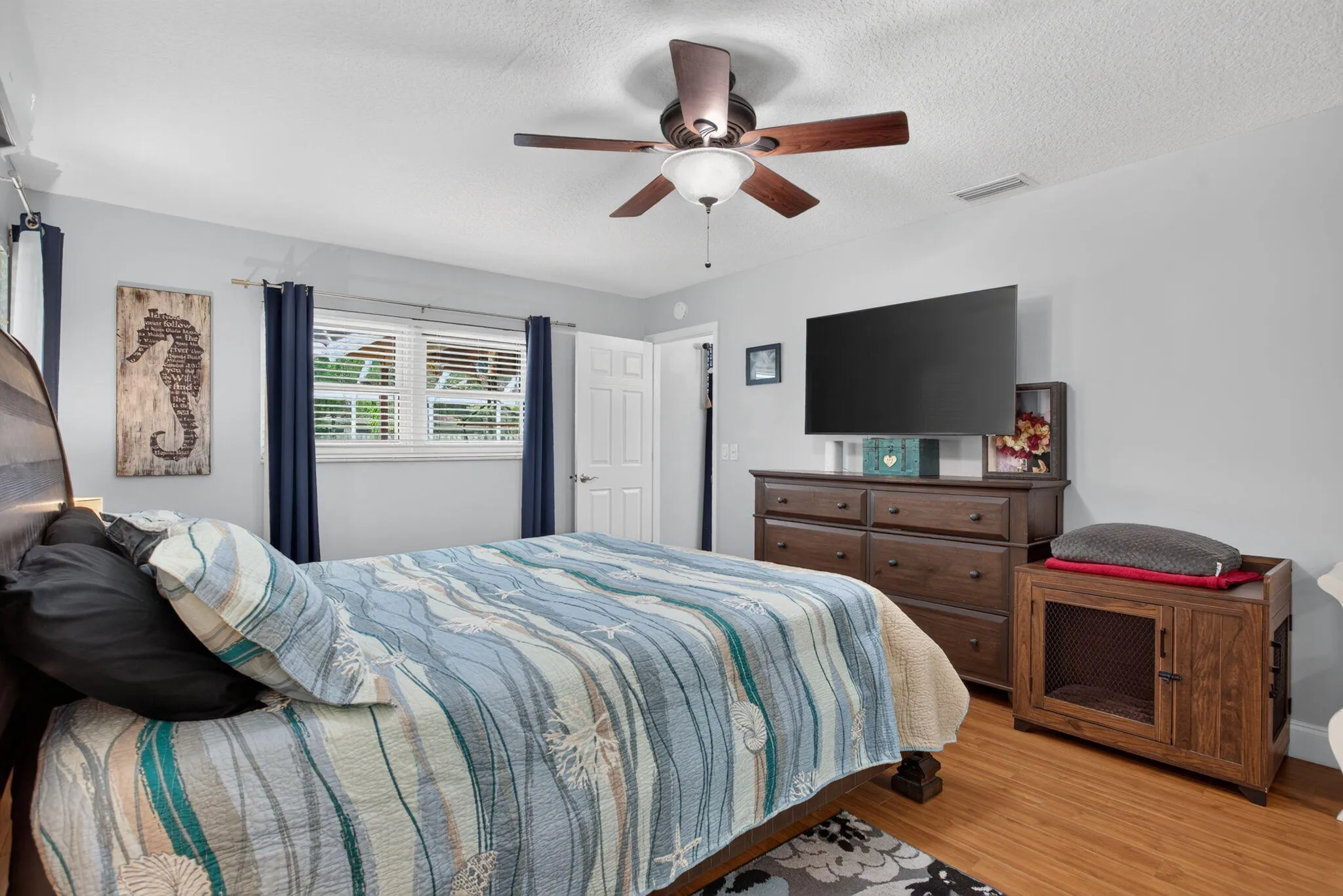 Wood-finish flooring, ceiling fan with light fixture, window with blinds, and white interior door