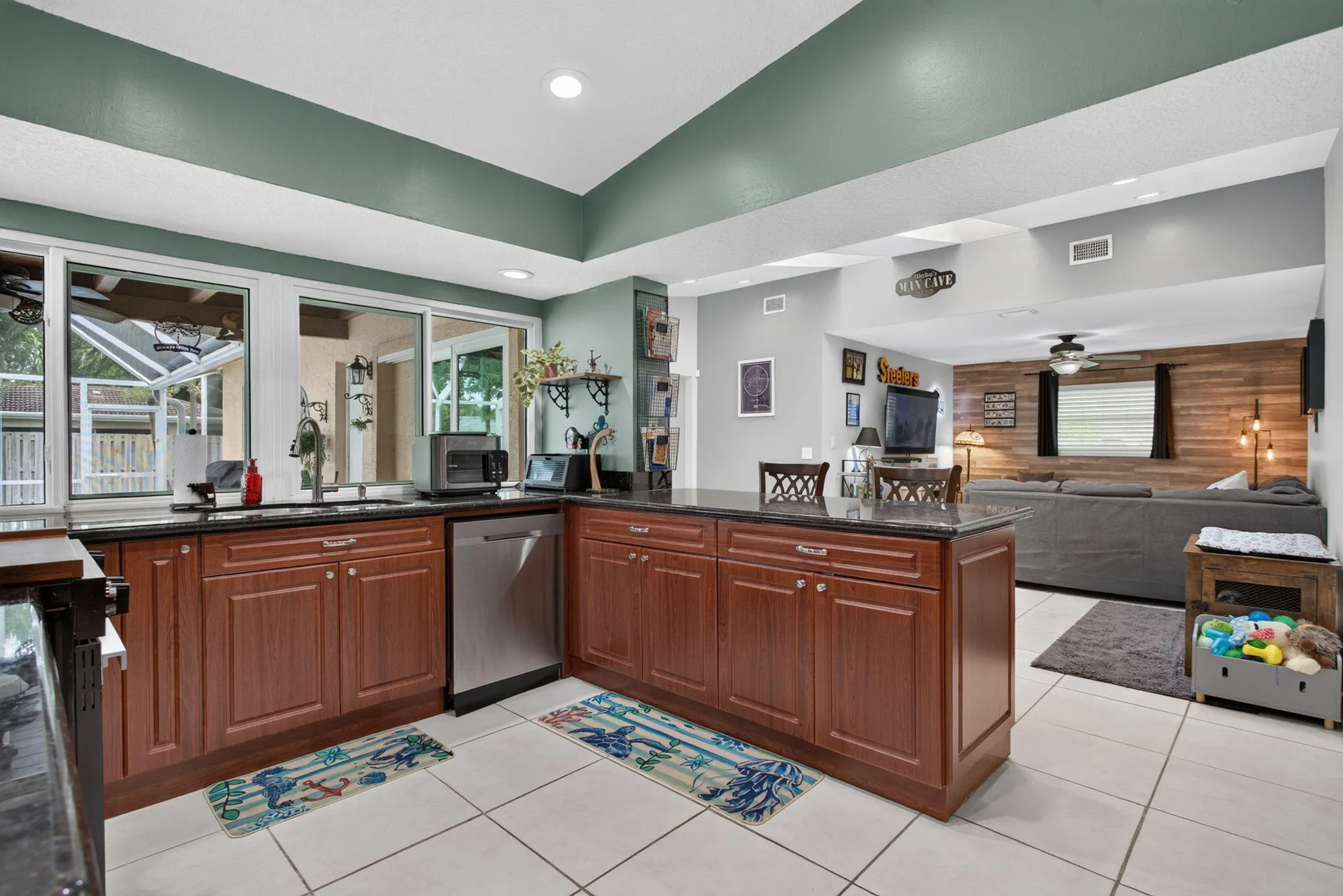 Kitchen featuring rich wood-finish cabinetry, dark countertops, a stainless steel dishwasher, and a center island