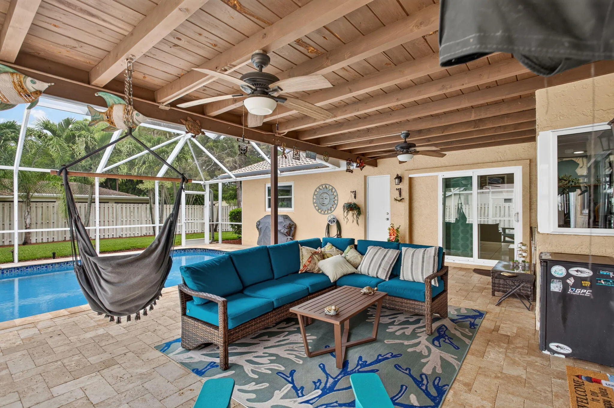 Covered outdoor patio with exposed wood beams, ceiling fans, and paver flooring