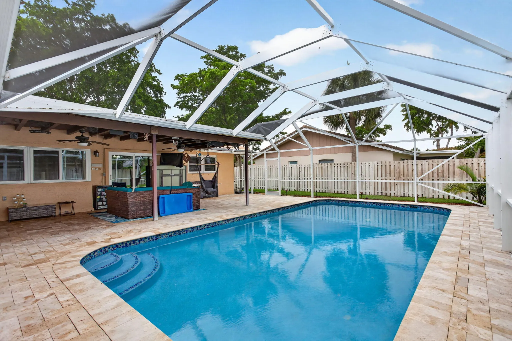 Screen-enclosed swimming pool with paver decking and integrated steps