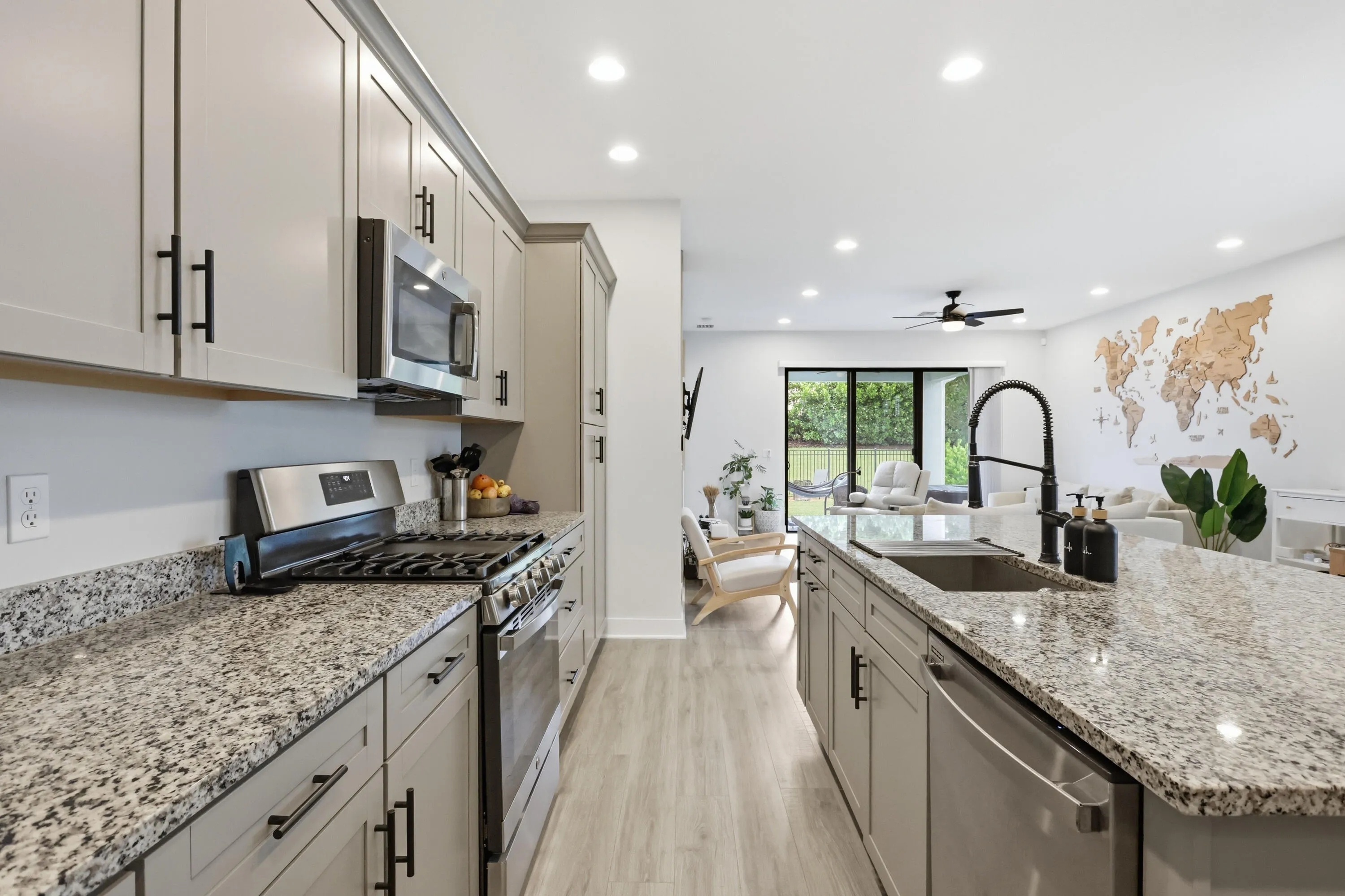 Modern kitchen featuring light cabinetry, stainless steel appliances, speckled stone countertops, and recessed lighting
