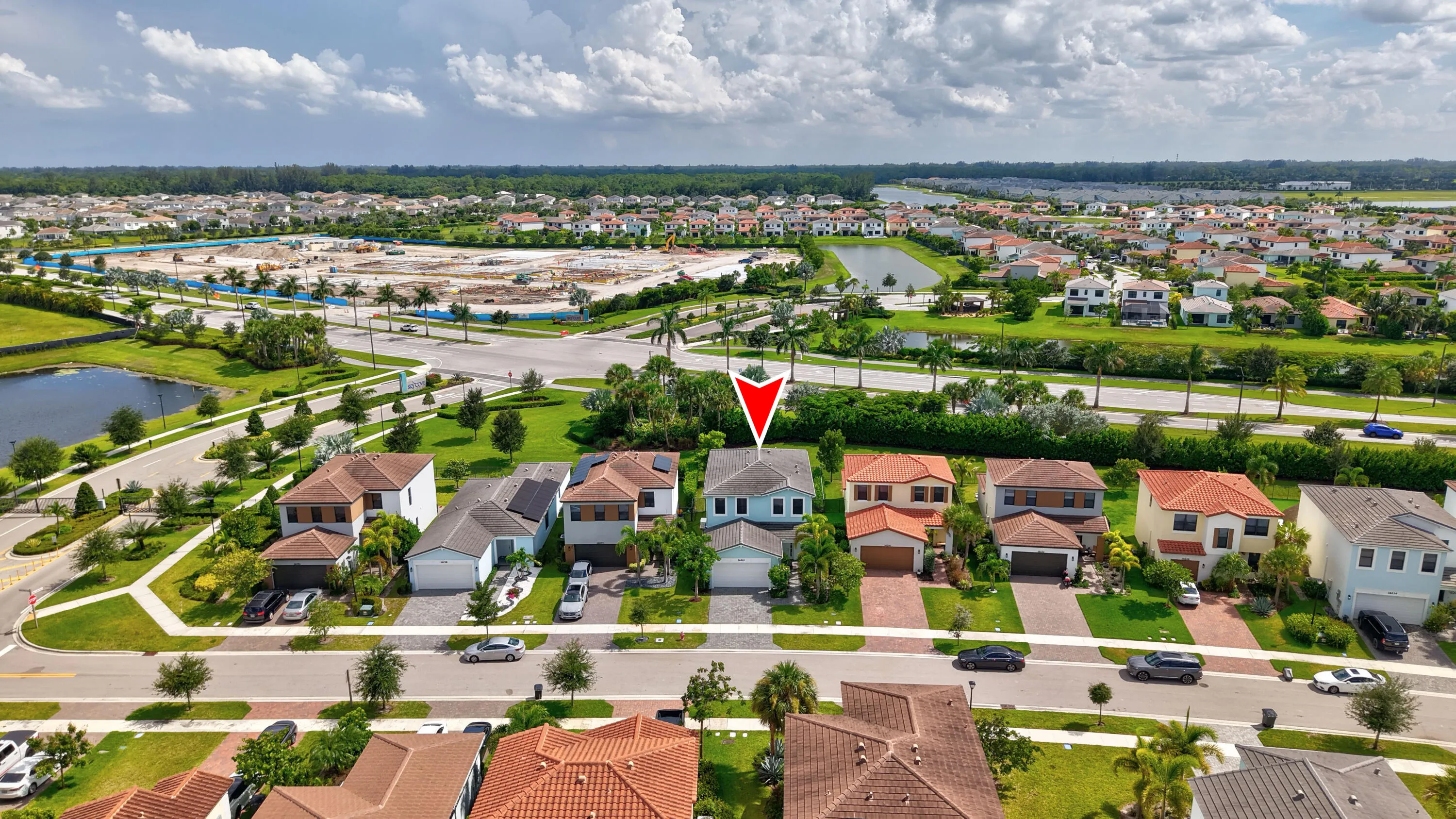 Aerial perspective highlighting the property within a residential development, featuring a water element and developing infrastructure