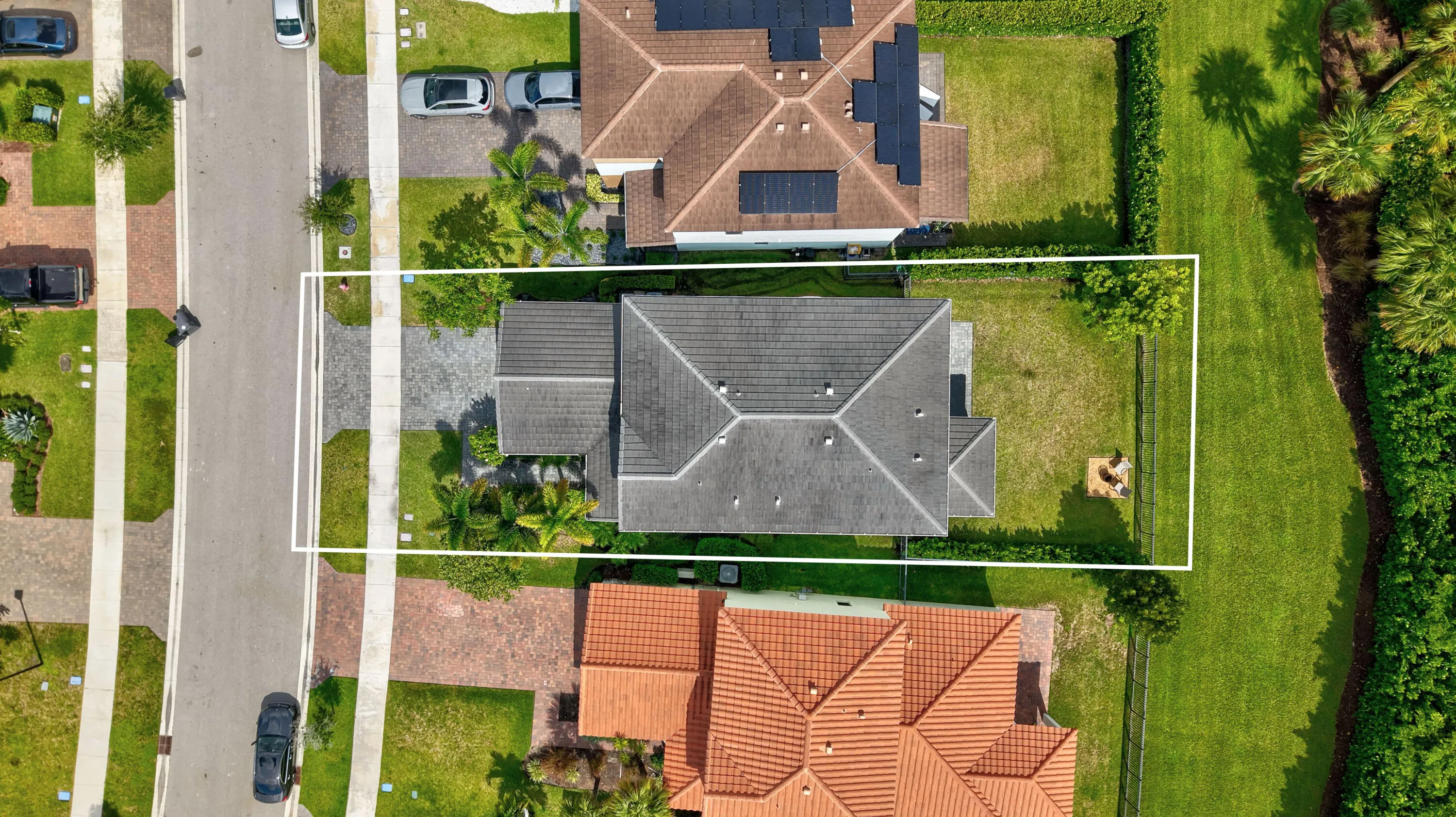 Gabled roofline, paver driveway, manicured lawn, and lush landscaping