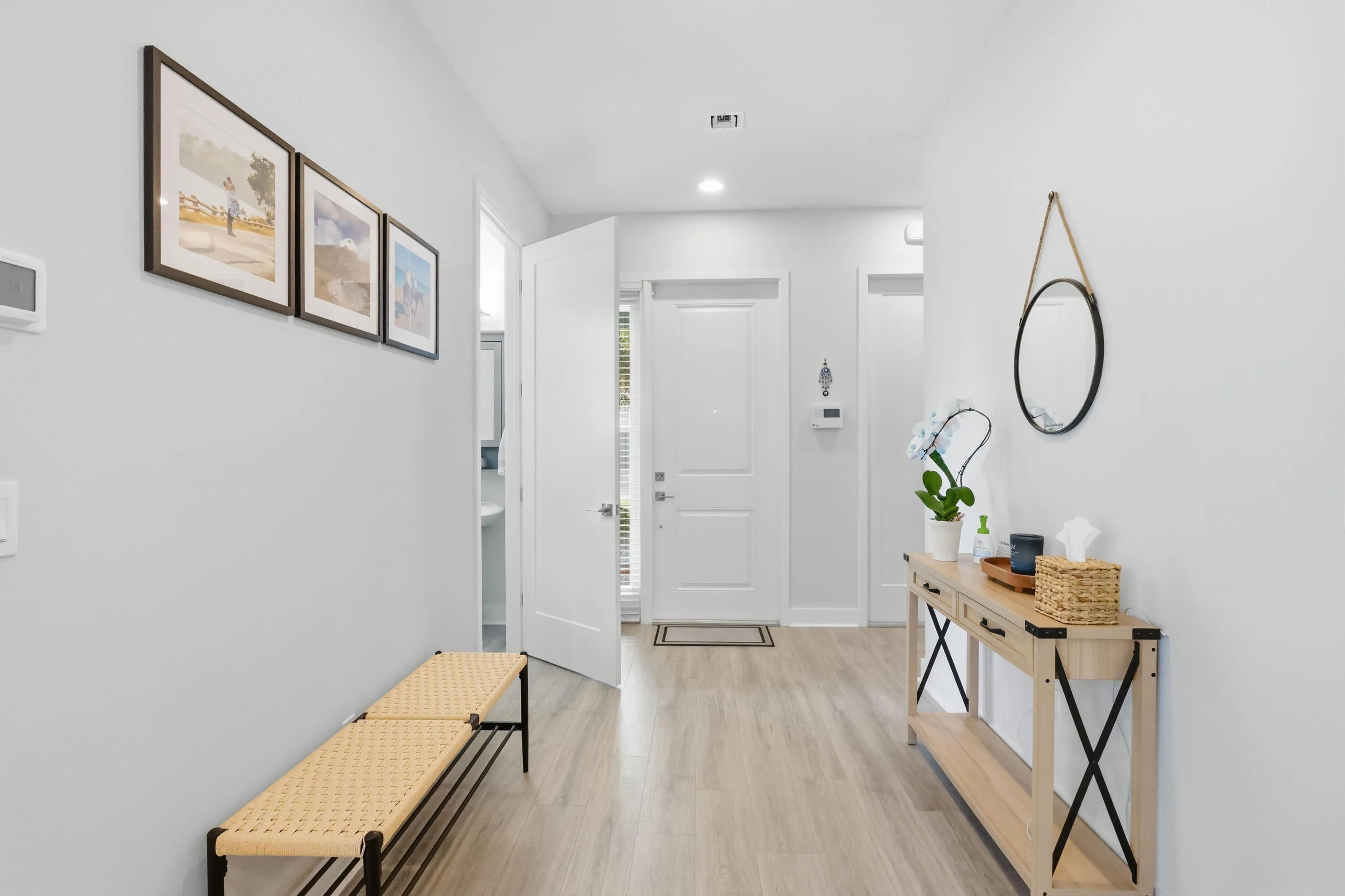 Recessed lighting illuminates the foyer featuring light wood-finish flooring and neutral wall tones