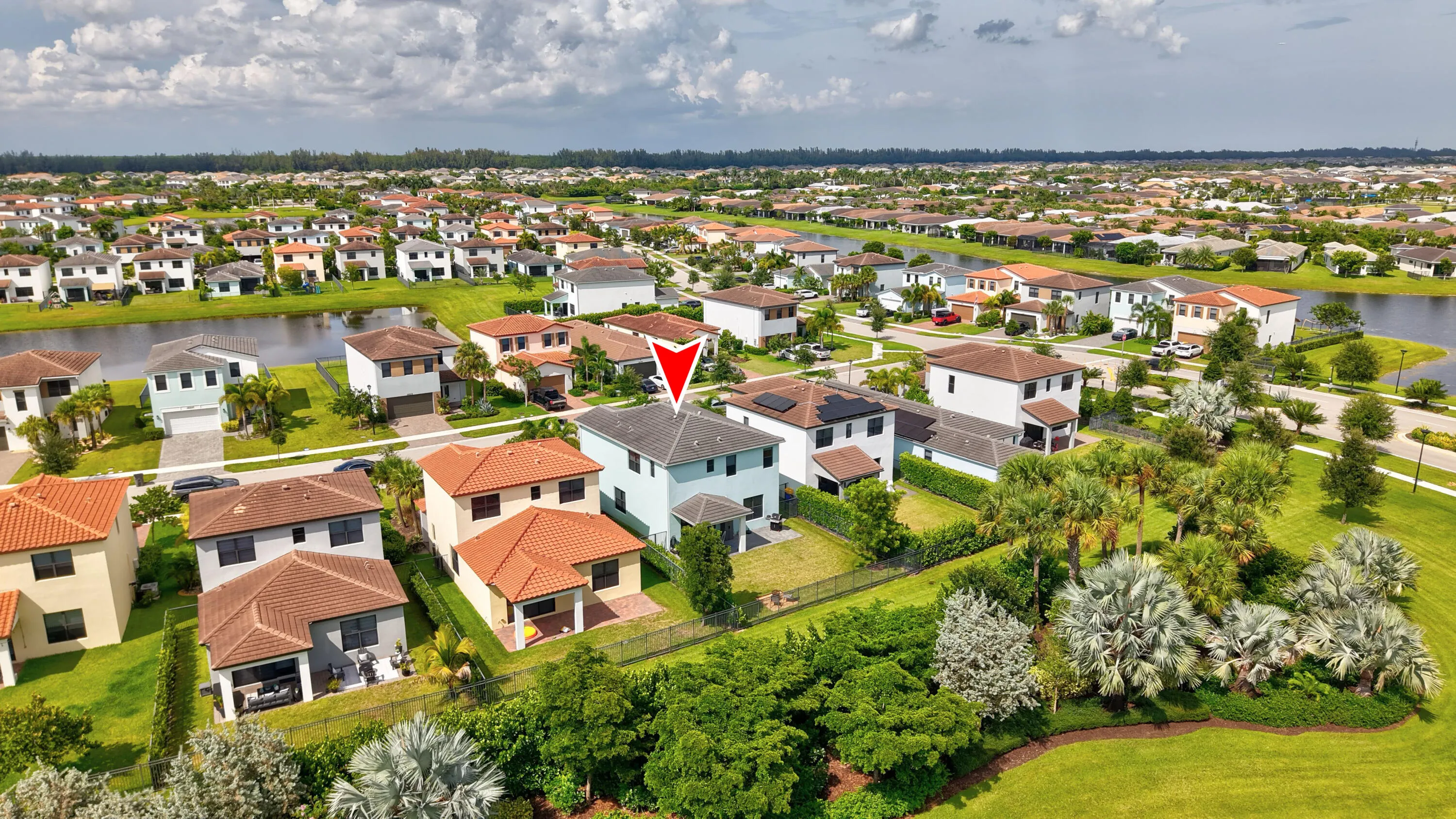 Aerial perspective showcasing the property's location within a residential community, featuring a lake, and mature landscaping