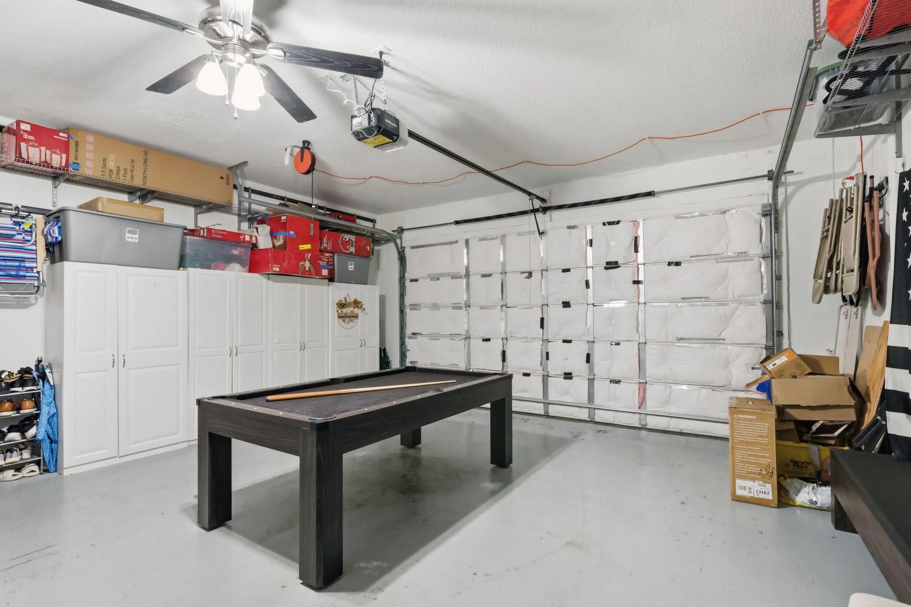 Garage with painted concrete flooring and a ceiling fan with integrated lighting