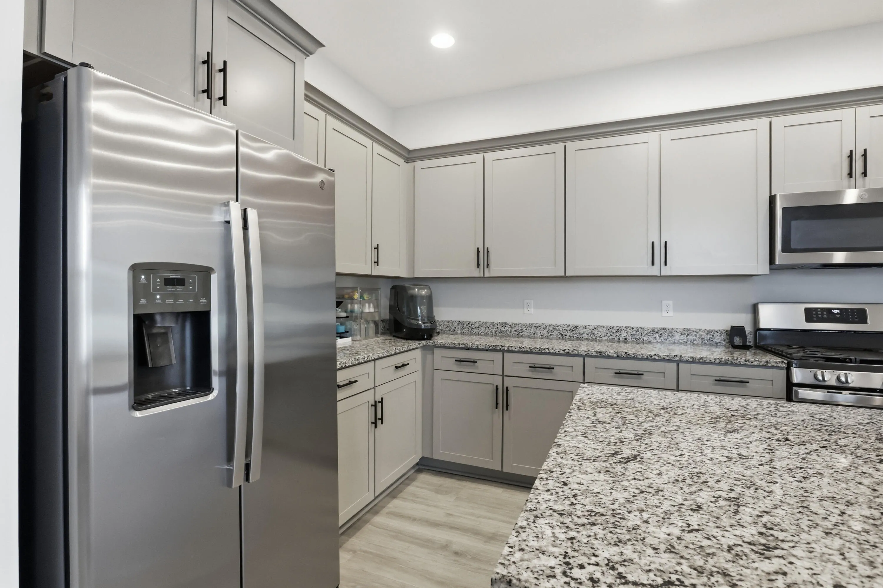 Stainless steel appliances, light gray cabinetry, granite countertops, and wood-finish flooring