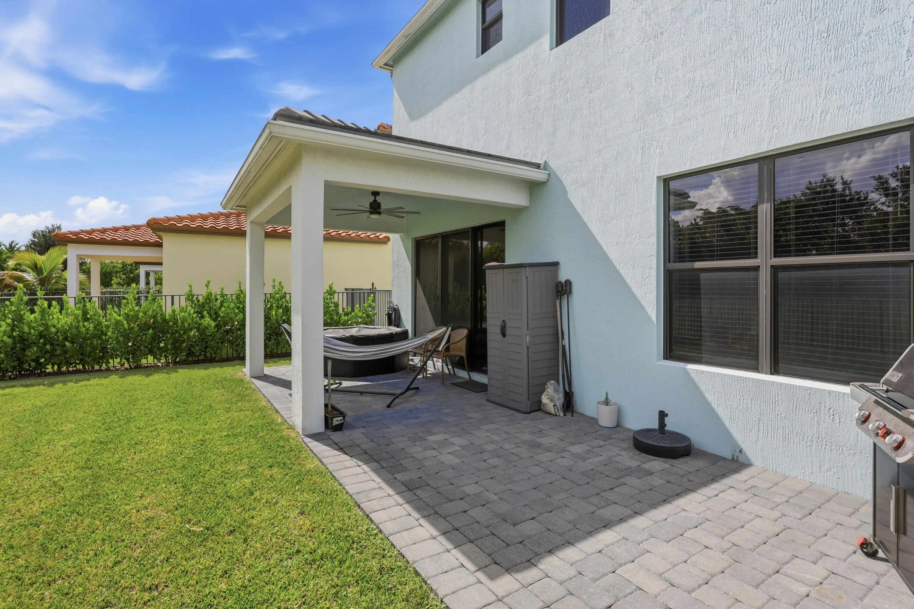 Covered patio with a ceiling fan, sliding glass door, and paver flooring