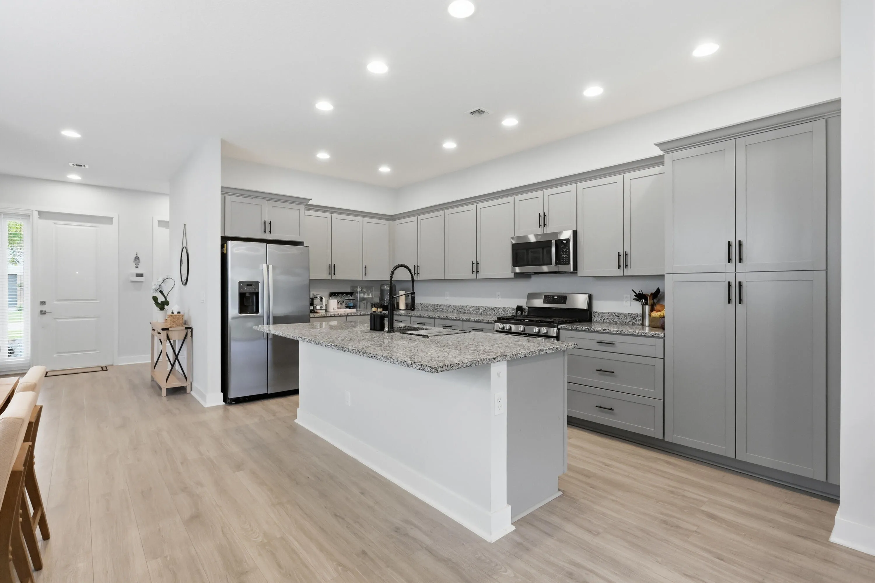 Kitchen featuring a central island, light gray cabinetry, stainless steel appliances, and light wood-finish flooring