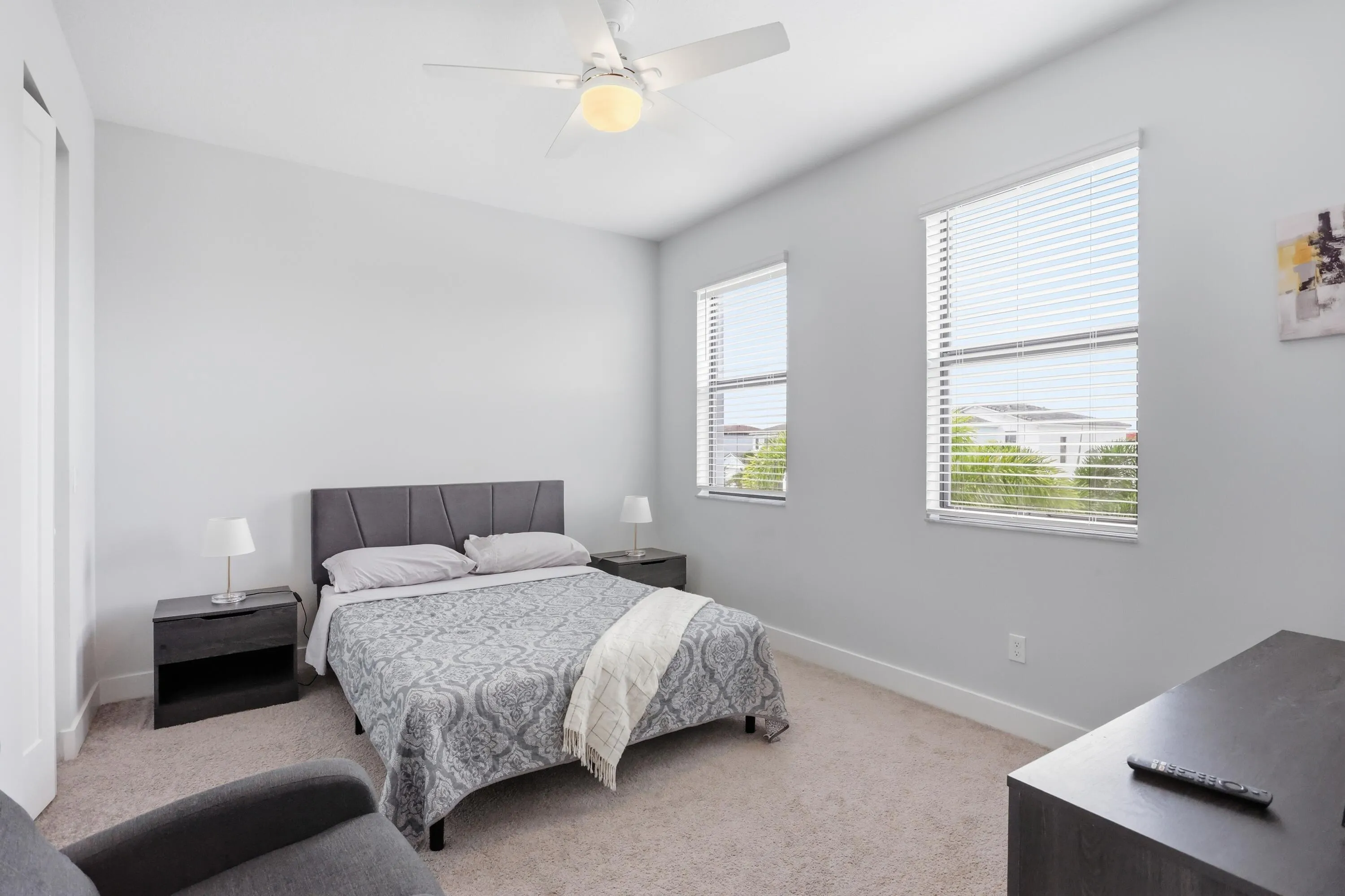 Neutral-toned room with carpeted flooring, two windows, a ceiling fan, and a built-in closet