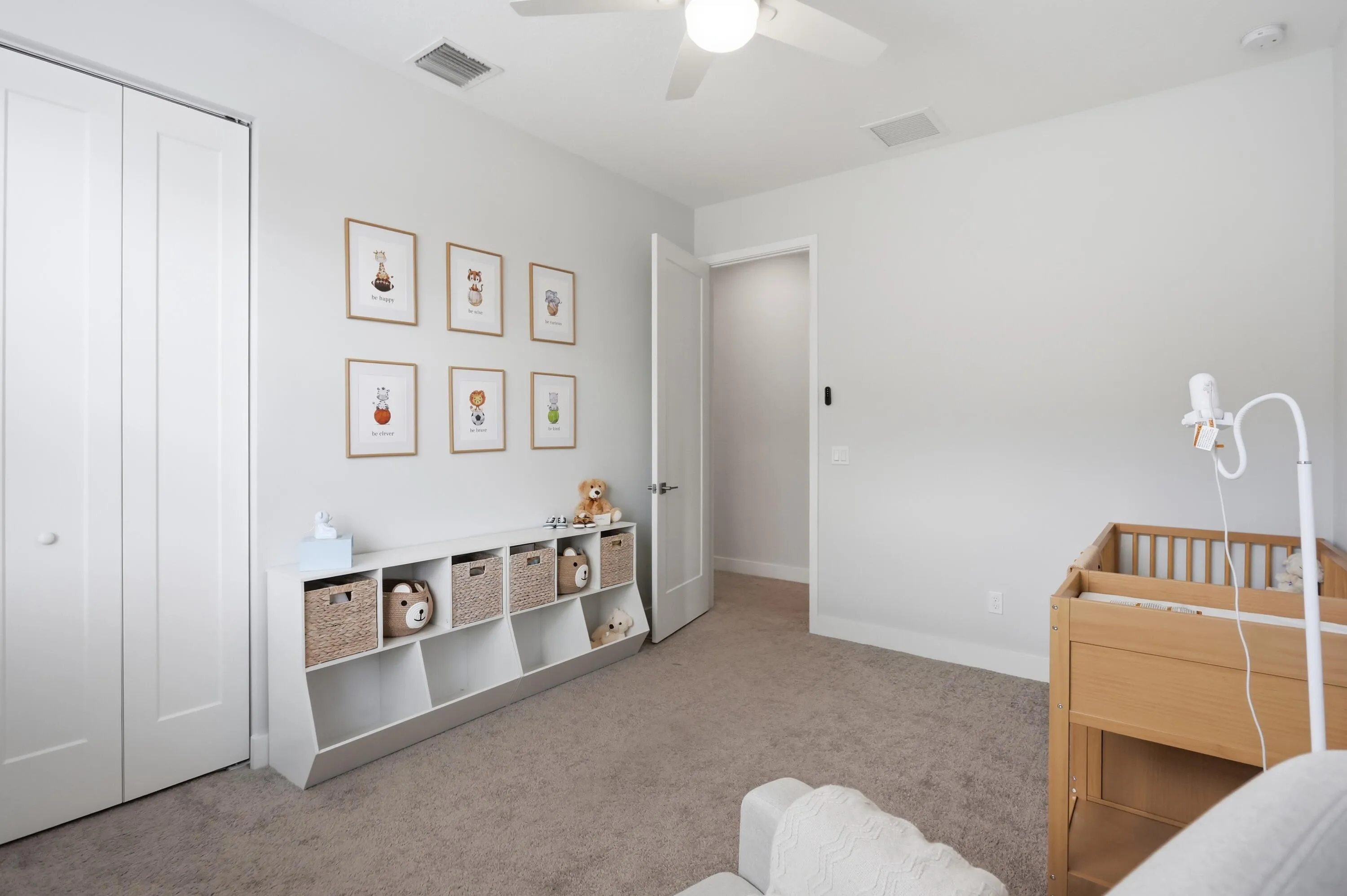 Neutral wall tones, carpeted flooring, a ceiling fan with integrated lighting, and a white bi-fold closet door