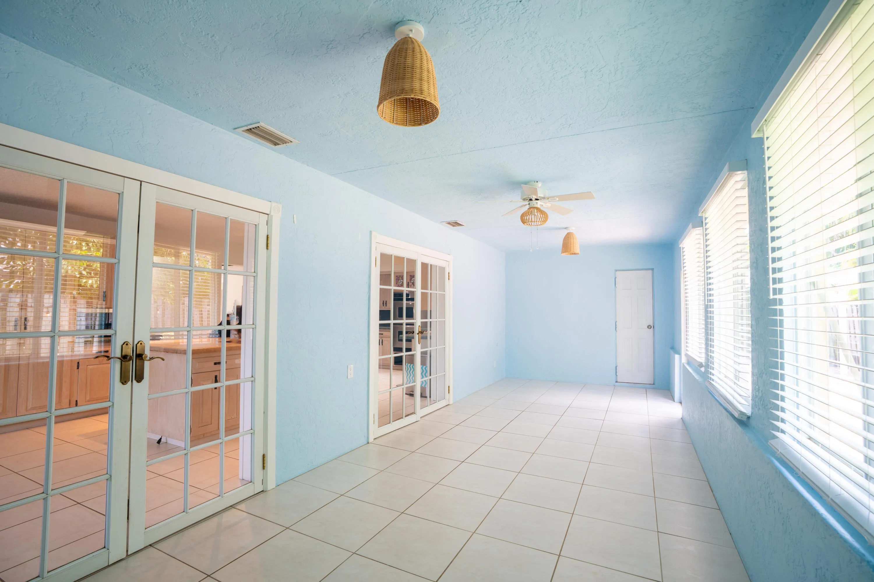Expansive room featuring light blue walls, white tile flooring, and multiple glass-paned doors
