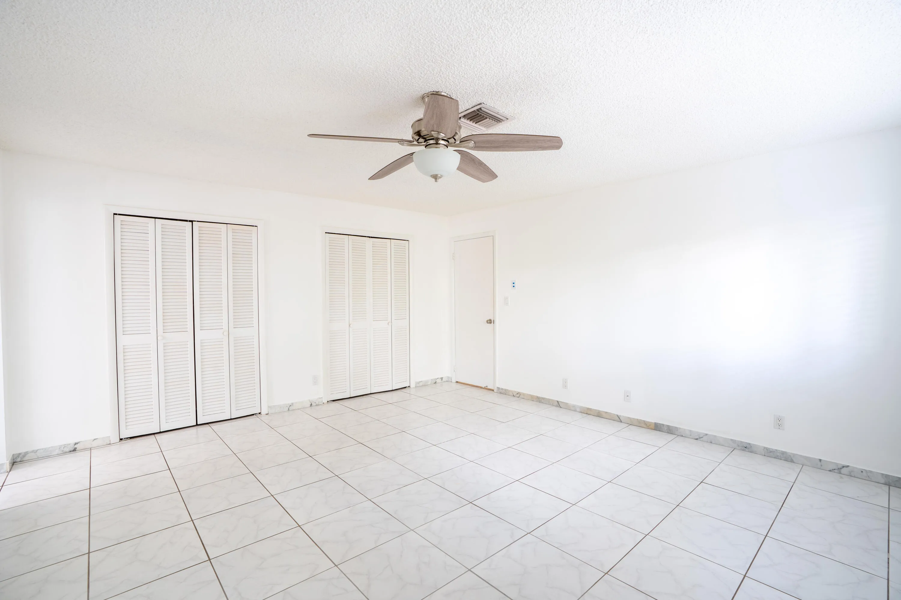 White tiled flooring, dual louvered bifold closet doors, and ceiling fan with integrated lighting