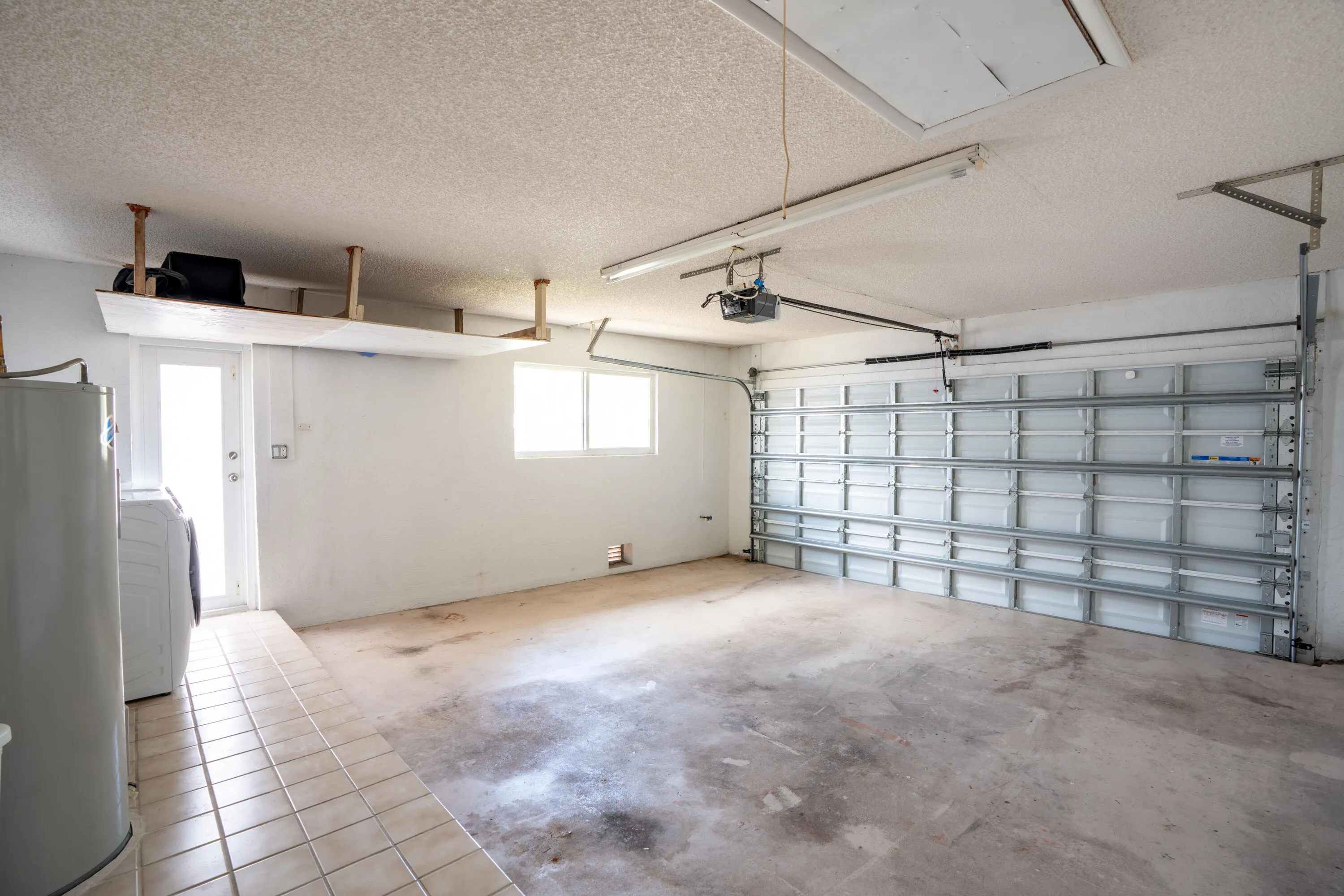 Garage with overhead storage, a garage door, tiled flooring, and a side access door
