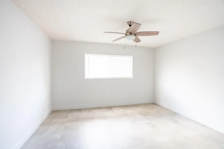 Bright interior with wood-finish flooring, a window with blinds, and a ceiling fan with light