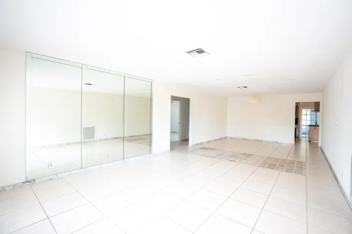 Spacious room featuring tile flooring, mirrored wall accents, a recessed ceiling light, and an overhead light fixture