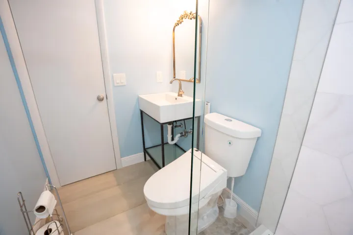 Wall-mounted vanity with a rectangular basin, gold-tone faucet, and decorative mirror
