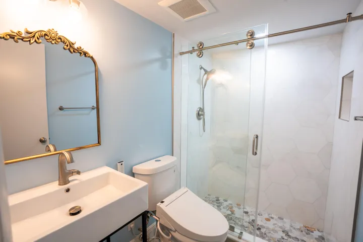 Floating vanity with a rectangular basin sink, brushed nickel faucet, and ornate gold-framed mirror