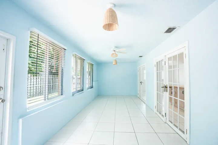 Long hallway with large windows, white tile flooring, and multiple sets of French doors