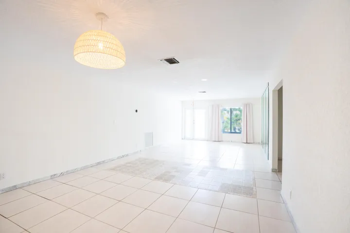 Expansive interior space featuring tile flooring, white walls, and a woven pendant light fixture