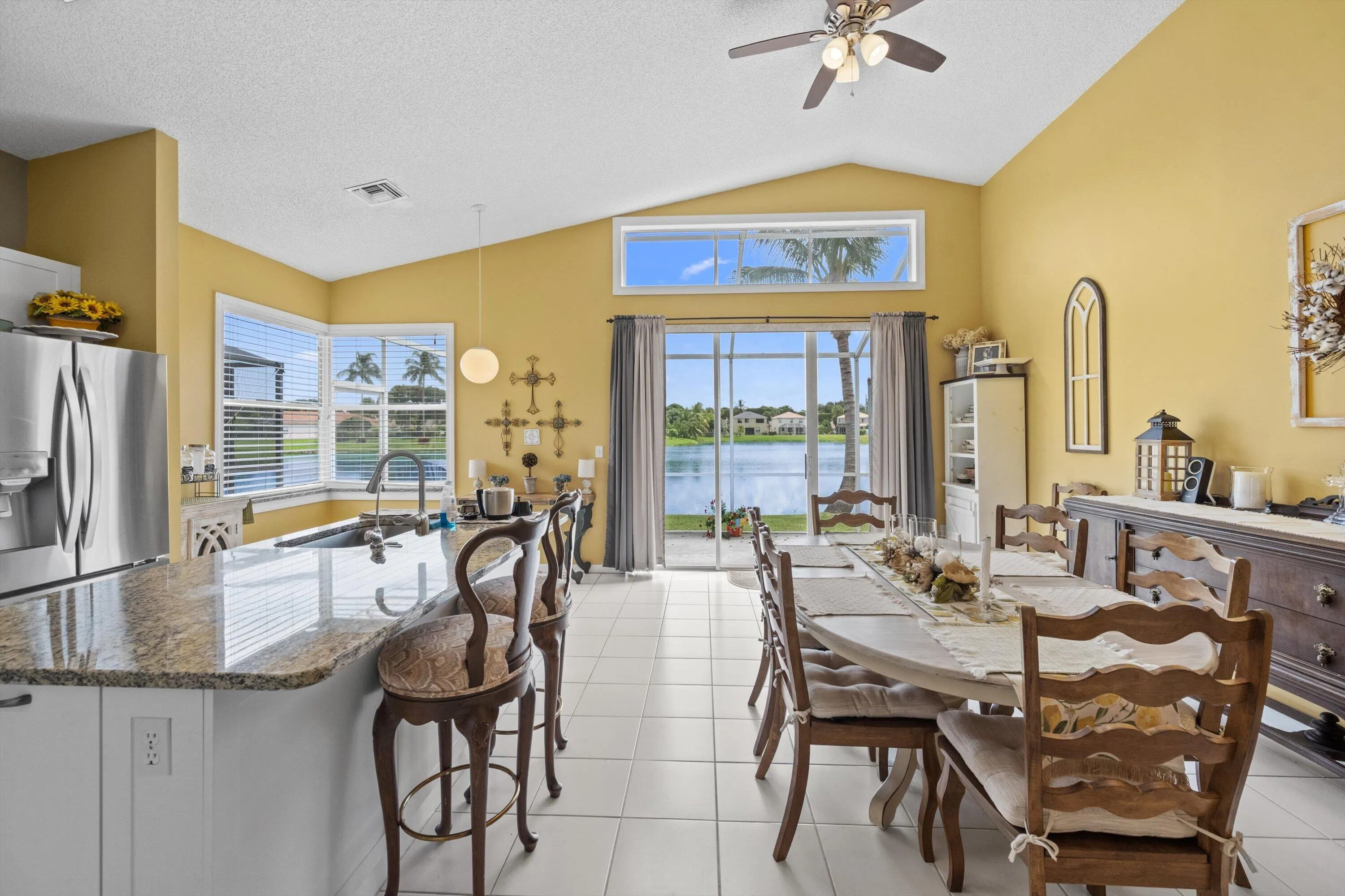Vaulted ceilings, white tile flooring, stainless steel appliances, granite countertops, and water views