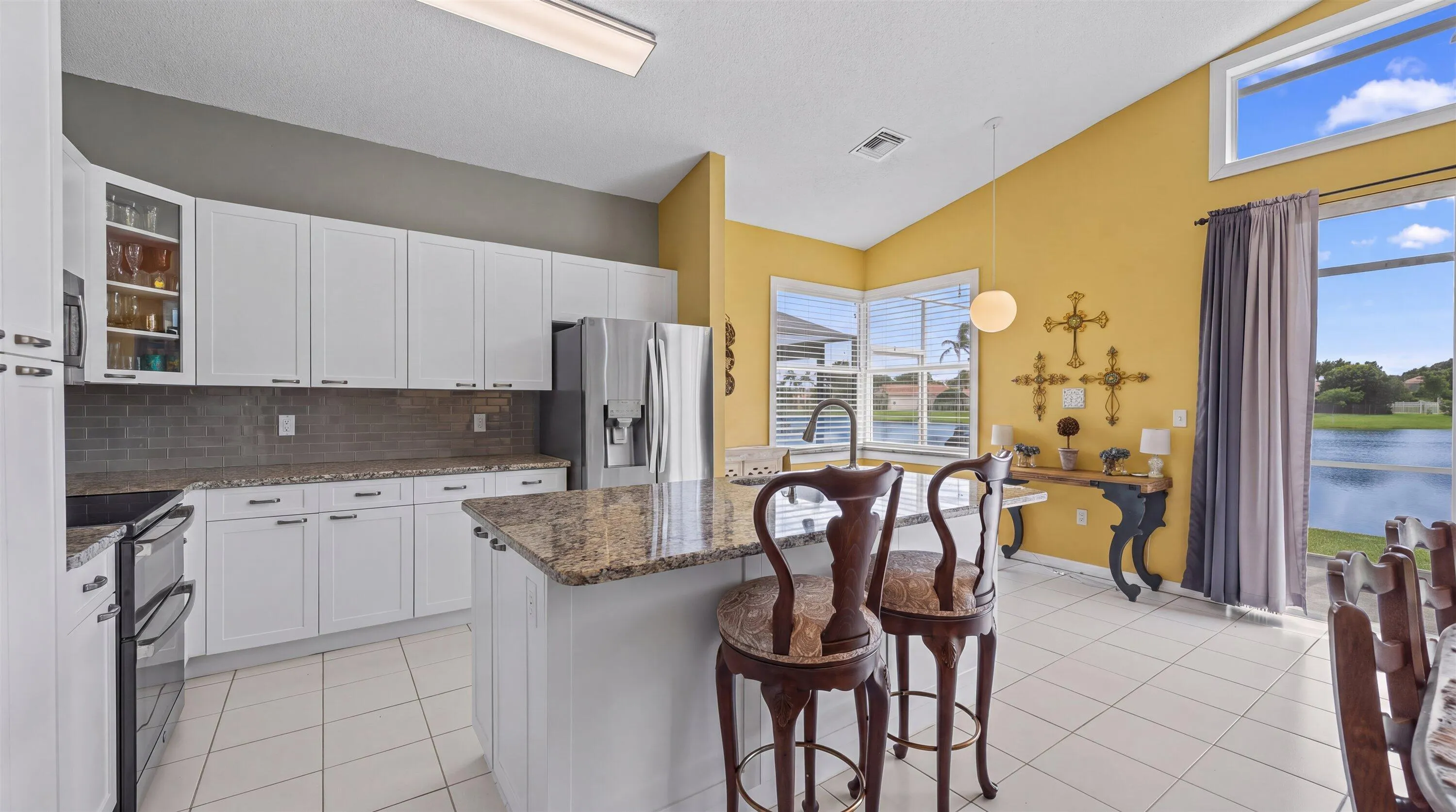 White cabinetry with dark hardware, granite countertops, tile flooring, and a large sliding glass door