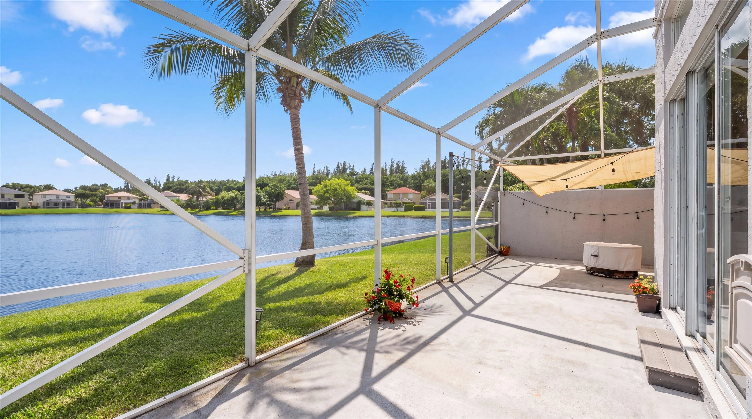Screened lanai featuring a concrete patio, sliding glass doors, and expansive water frontage